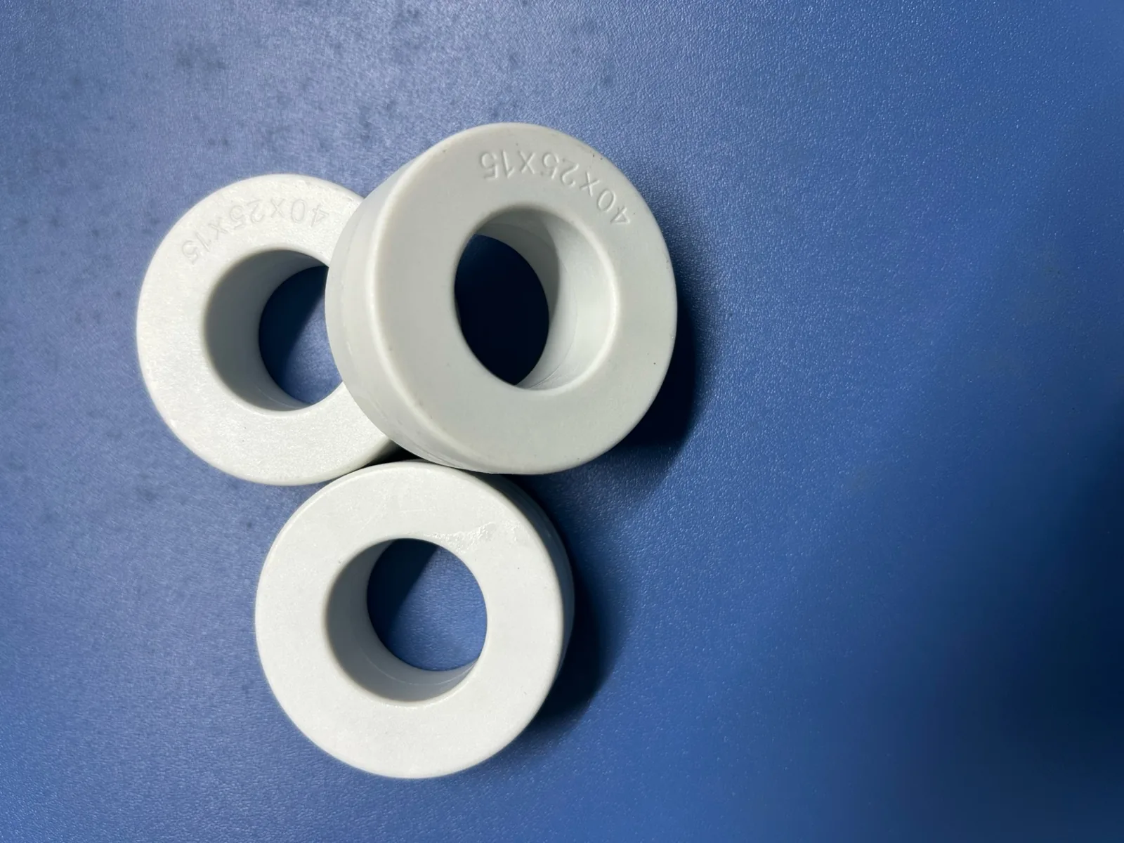 Three white-cased amorphous toroidal cores marked 40X25X15 on a blue surface