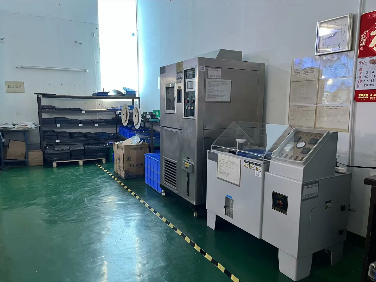 An environmental test chamber and a salt-spray test cabinet standing on a workshop floor