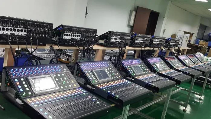 Rows of digital mixing consoles powered up on test benches at the SEIKAKU group plant in Dongguan
